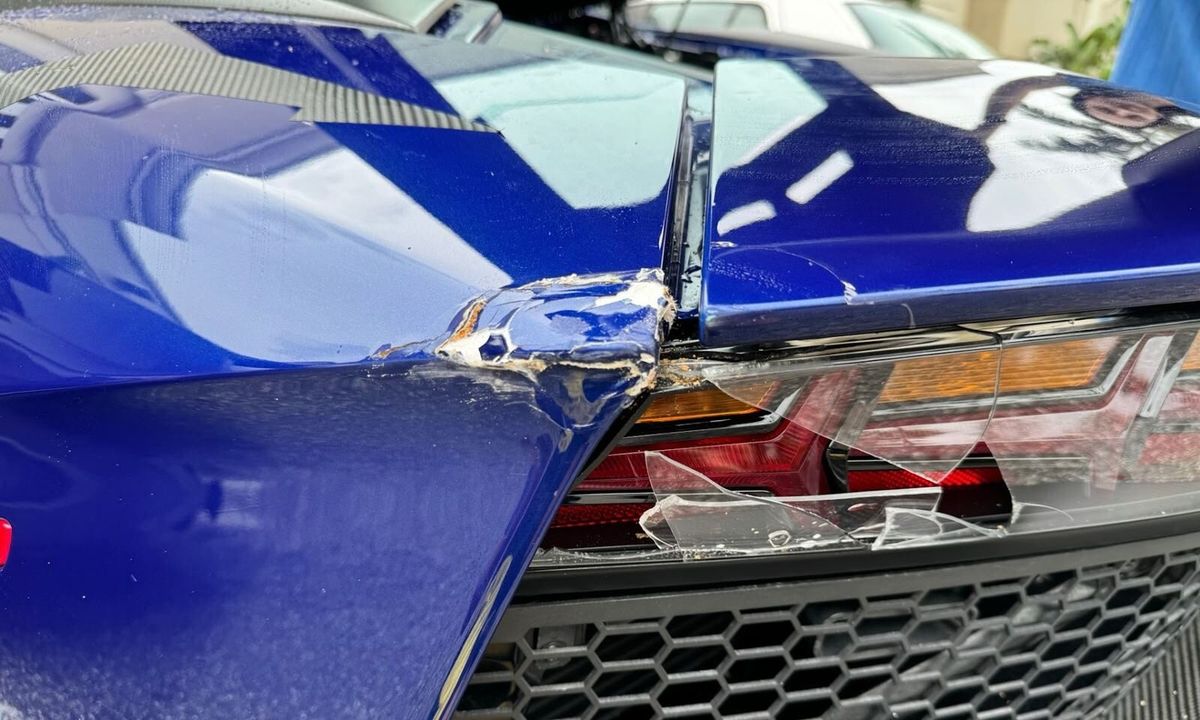 Blue Lamborghini Aventador SV with a crushed rear body corner and a shattered tail-lamp lens before repair at Gold Coast Collision Center, Pompano Beach