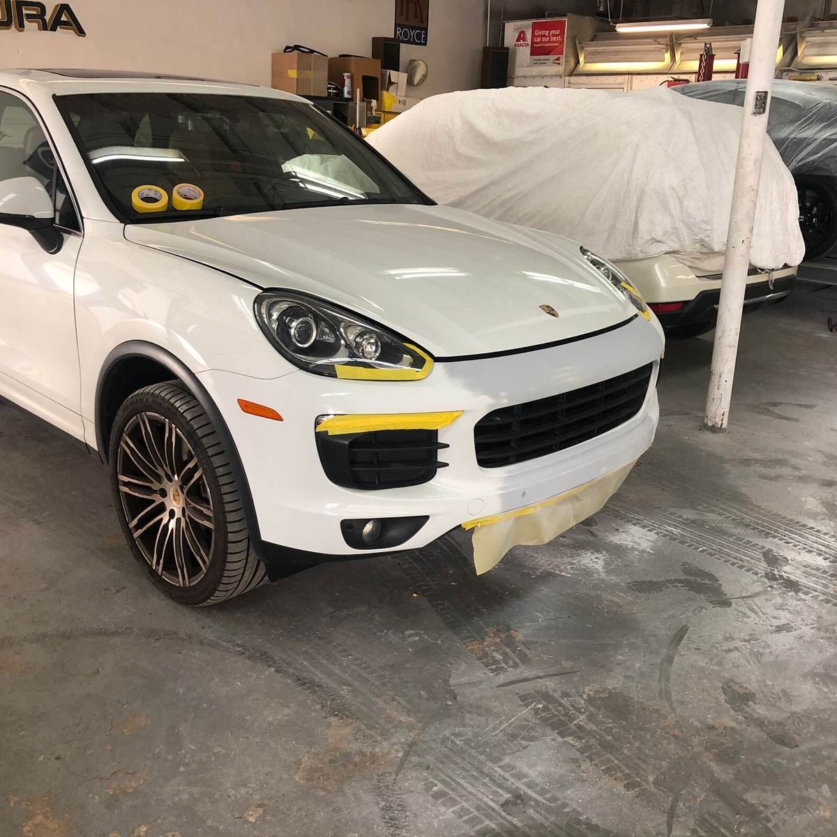White Porsche Cayenne masked for paint in the Gold Coast Collision Center refinish bay